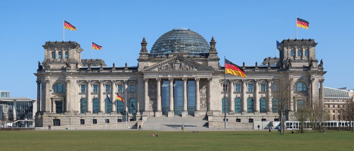 Das Reichstagsgebäude in Berlin mit wehenden Deutschlandflaggen, Sitz des Deutschen Bundestages.